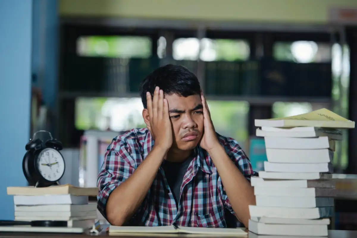 Tired student studying in a library during exam preparation, highlighting exam stress and the importance of emotional support for students.